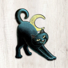 Load image into Gallery viewer, Illustration of a black cat stretching with a yellow crescent moon on a light wooden background