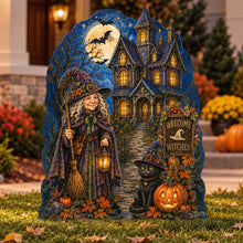 Load image into Gallery viewer, A Halloween yard sign shaped like a tombstone, featuring a haunted house under a full moon, a witch holding a broom and lantern, a black cat, pumpkins, and a 'Welcome to Witches' sign, displayed on grass in front of a house.