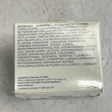 Load image into Gallery viewer, Back of a cosmetic product packaging with ingredient list on a gray surface