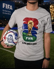 Load image into Gallery viewer, Person wearing a t-shirt with FIFA World Cup graphics on a soccer field.