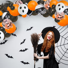 Load image into Gallery viewer, Woman in a Halloween costume with a broom, surrounded by balloons and decorations on a white wall.
